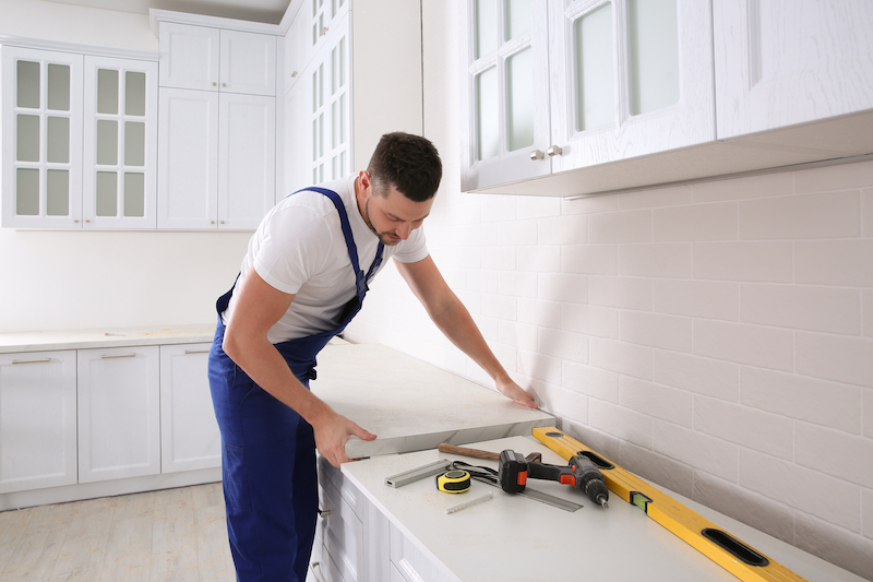 Worker installing new countertop in modern kitchen