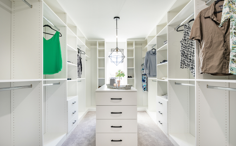 Beautifully staged walk in closet with custom white cabinets