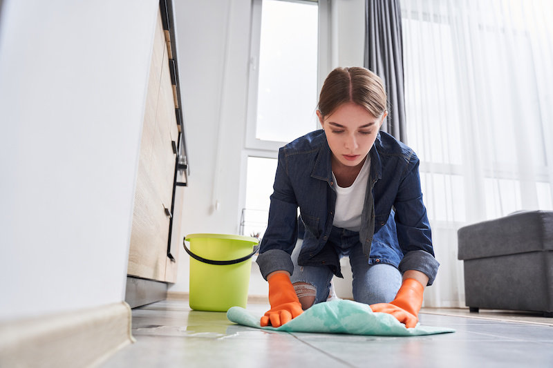 Woman cleaning up floor damage from water